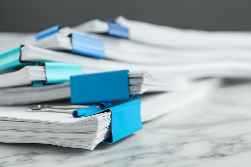 Stack of documents with binder clips on marble table, closeup