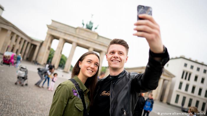 A couple poses for a photo in front of the Brandenburg Gate in Berlin, Germany (picture-alliance/dpa/K. Nietfeld)
